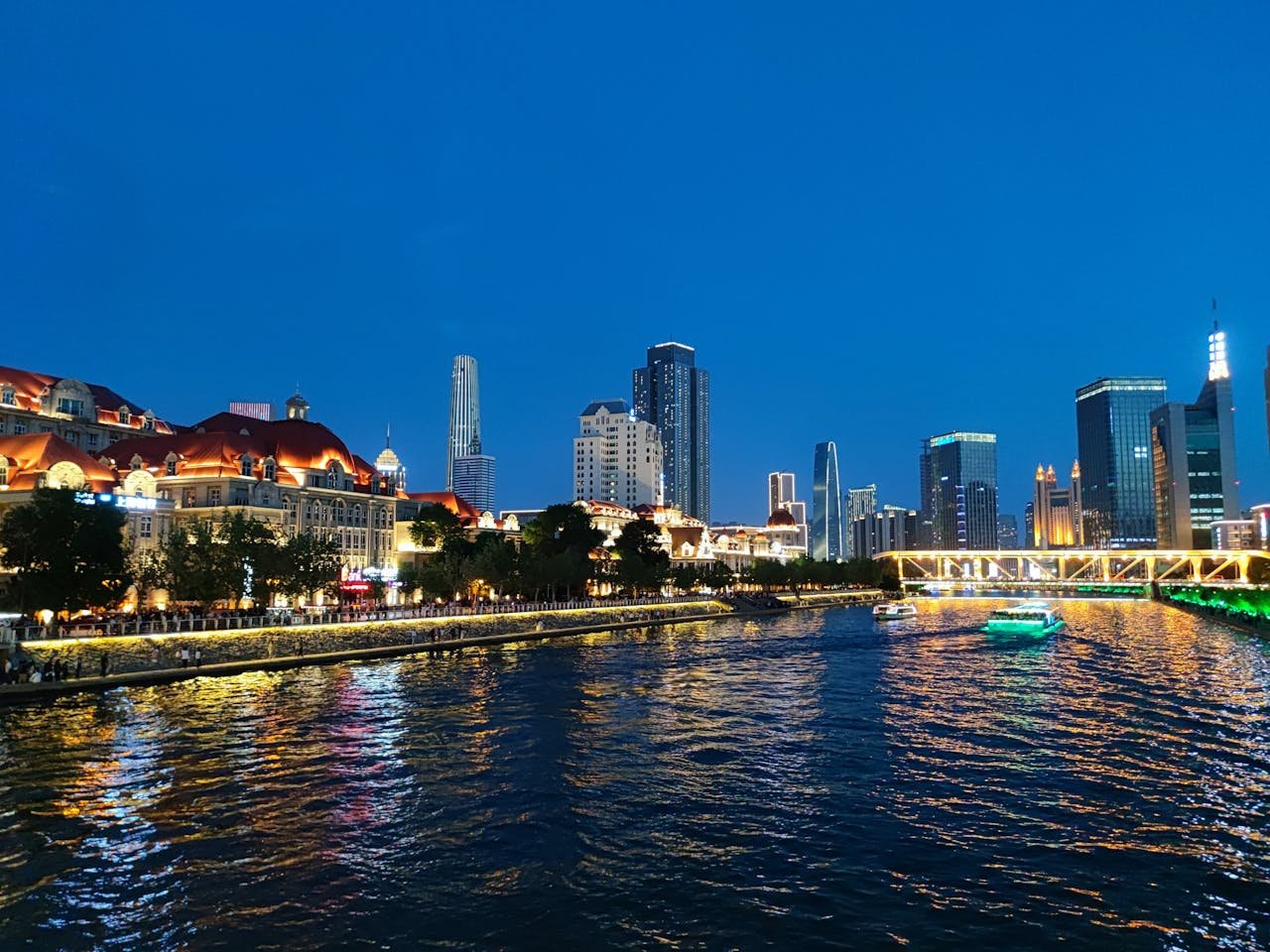 Stunning view of the Tianjin skyline and illuminated buildings reflecting on Hai River at night.